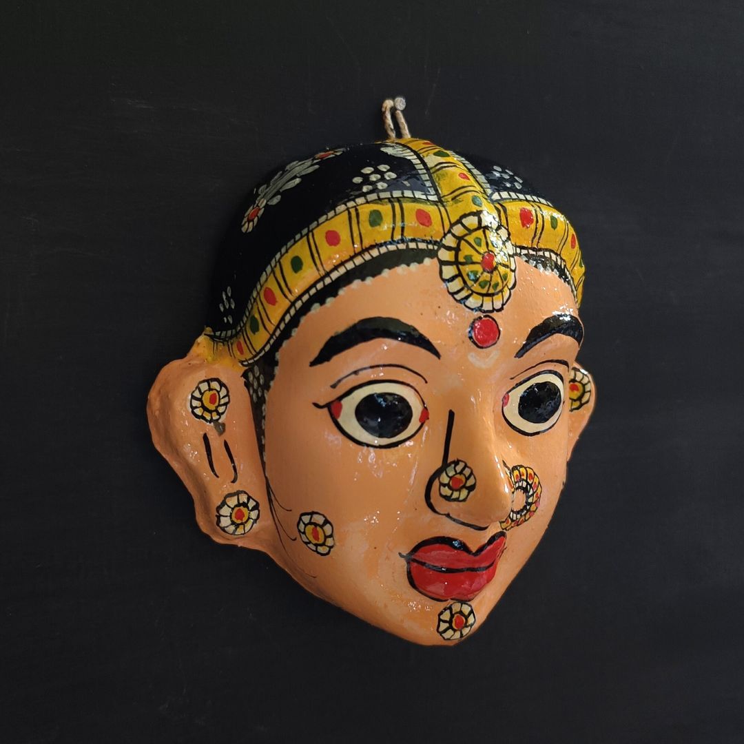 classic female cheriyal mask with crayola peach color face wearing ornaments