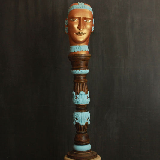 hand crafted wooden bust of a mystery women with gold color is placed on a wooden holder