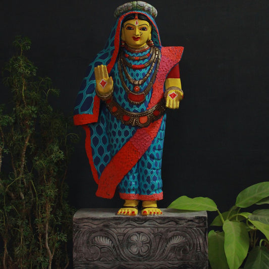 hand carved wooden artifact of devi is painted in a yellow color and blue saree with design giving it a modern look