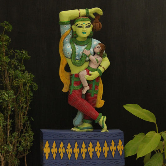 a wooden artifact of a mother holding her child is painted in vibrant green blue red and navy blue 